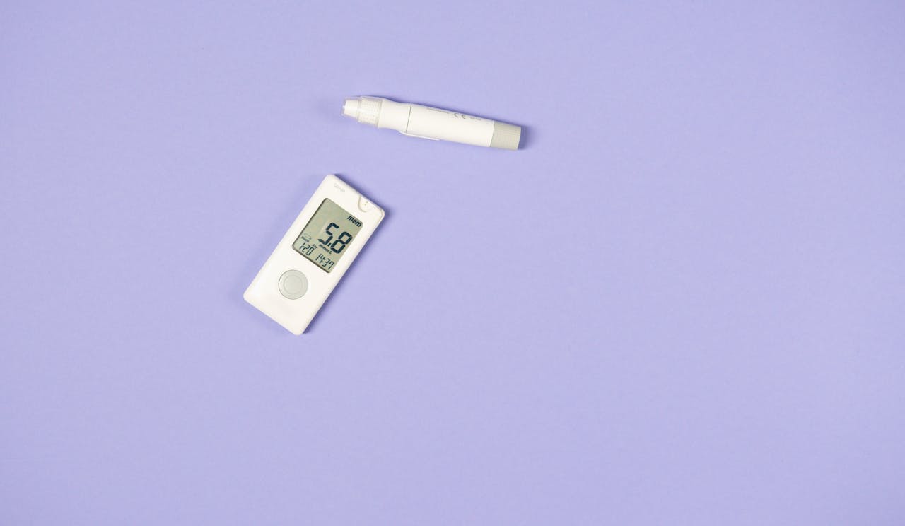 services-02 White glucometer and lancet pen on light purple background for diabetes management.
